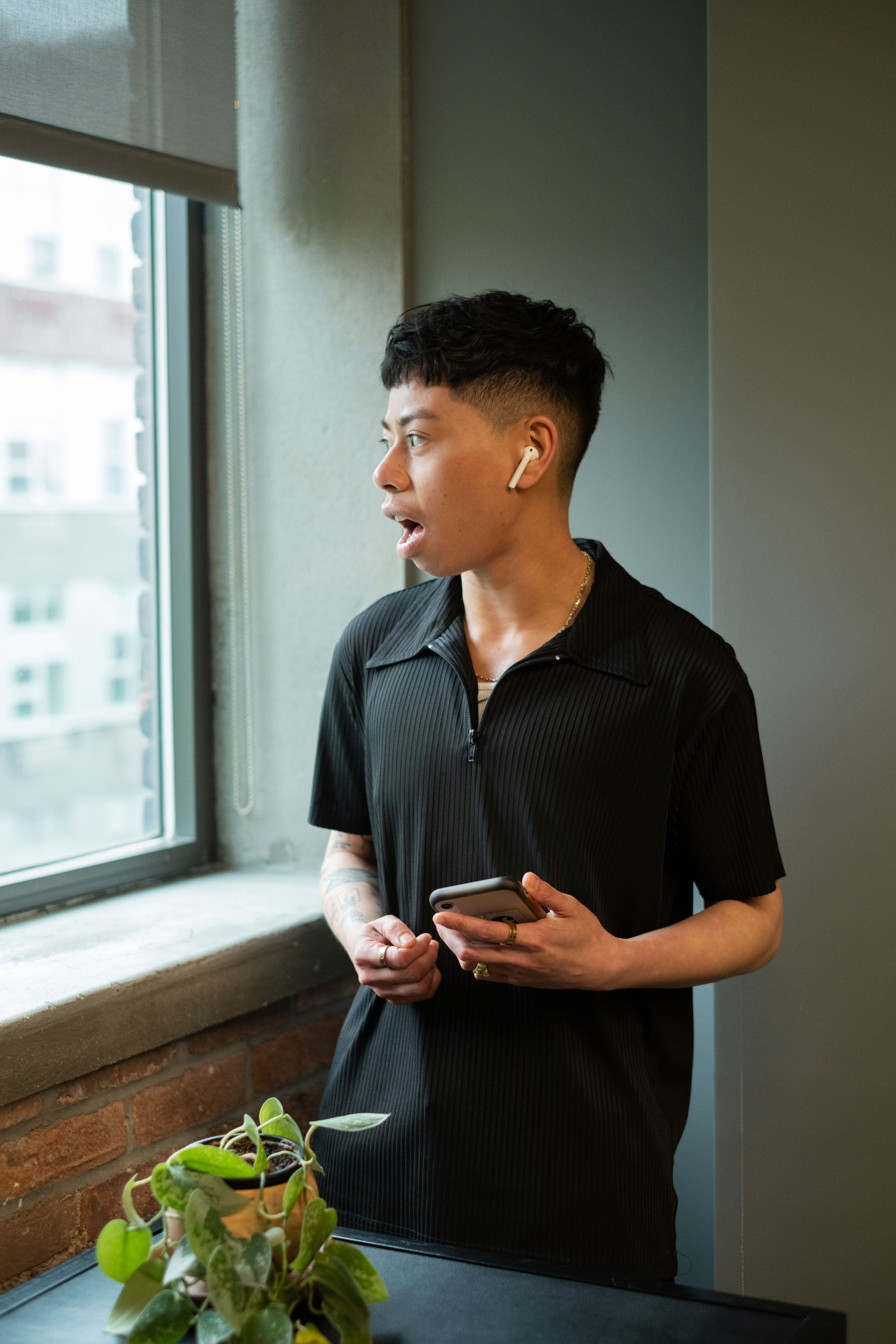 A surprised non-binary person looking out of a window